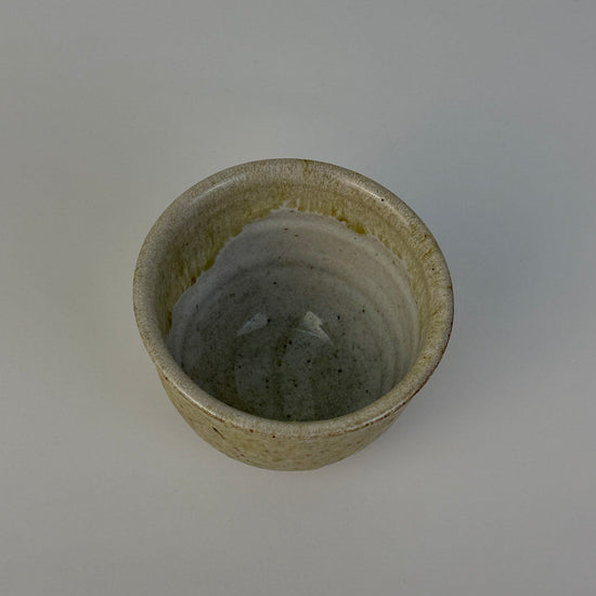 Small ceramic cup with a textured surface on a plain background