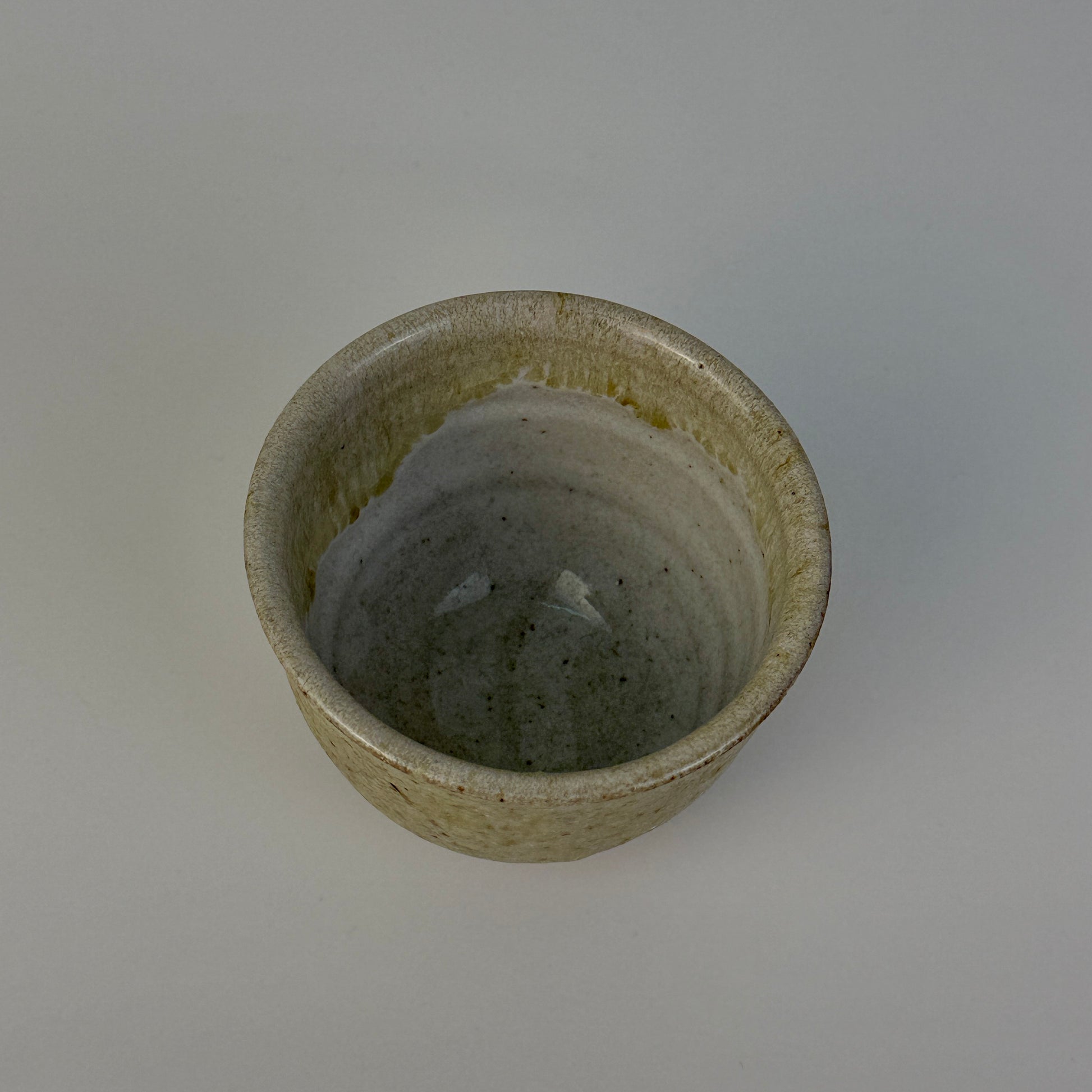 Small ceramic cup with a textured surface on a plain background