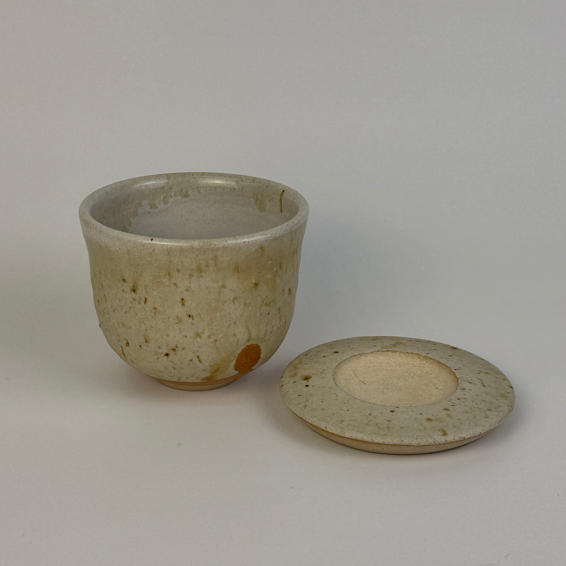 Ceramic cup and lid on a plain background