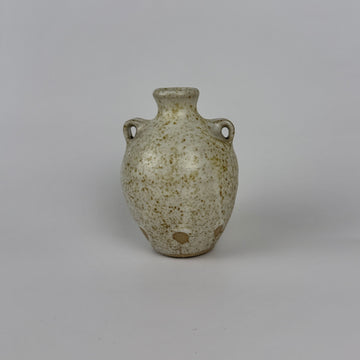 Small ceramic vase with speckled glaze on a gray background