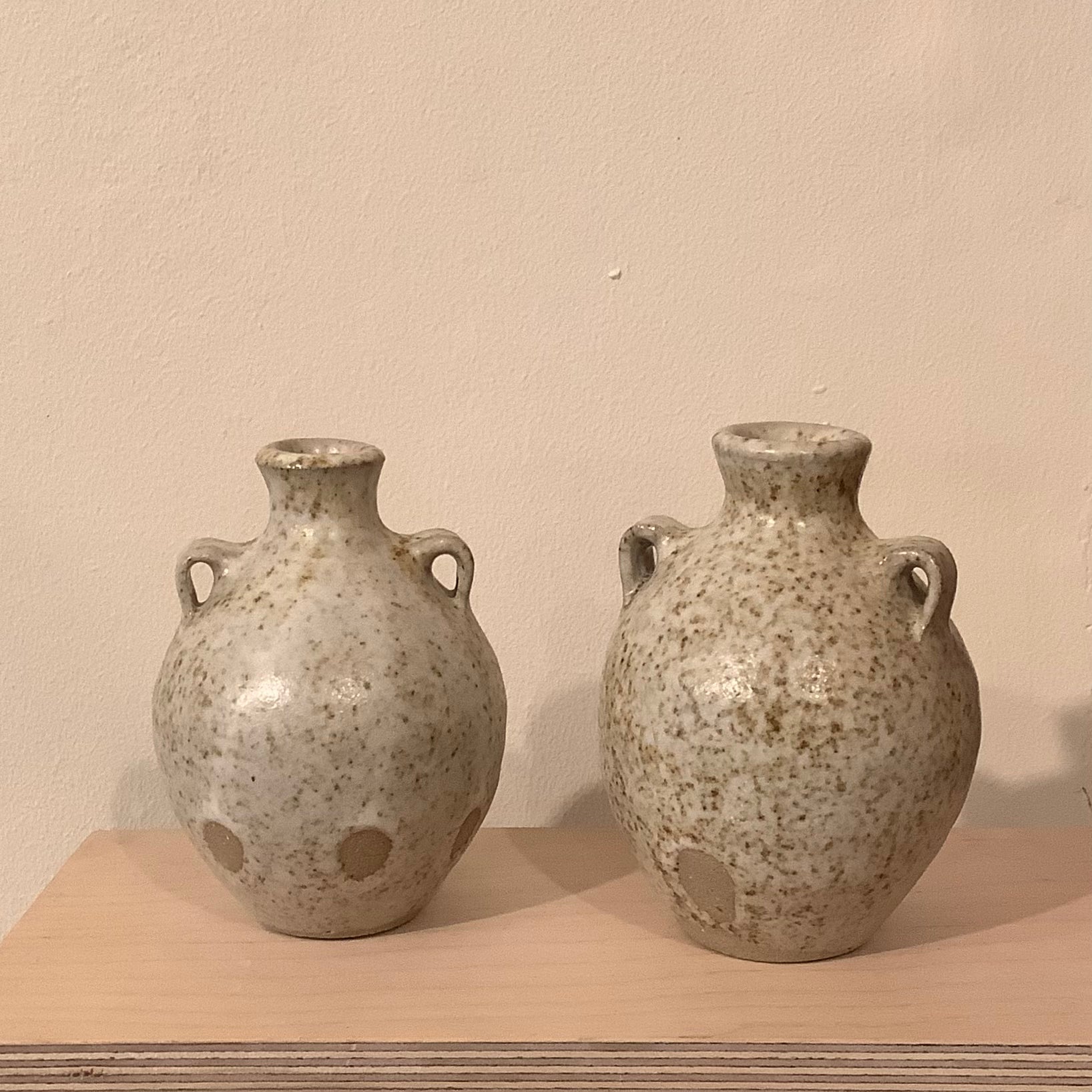 two ceramic budvases on a wooden shelf