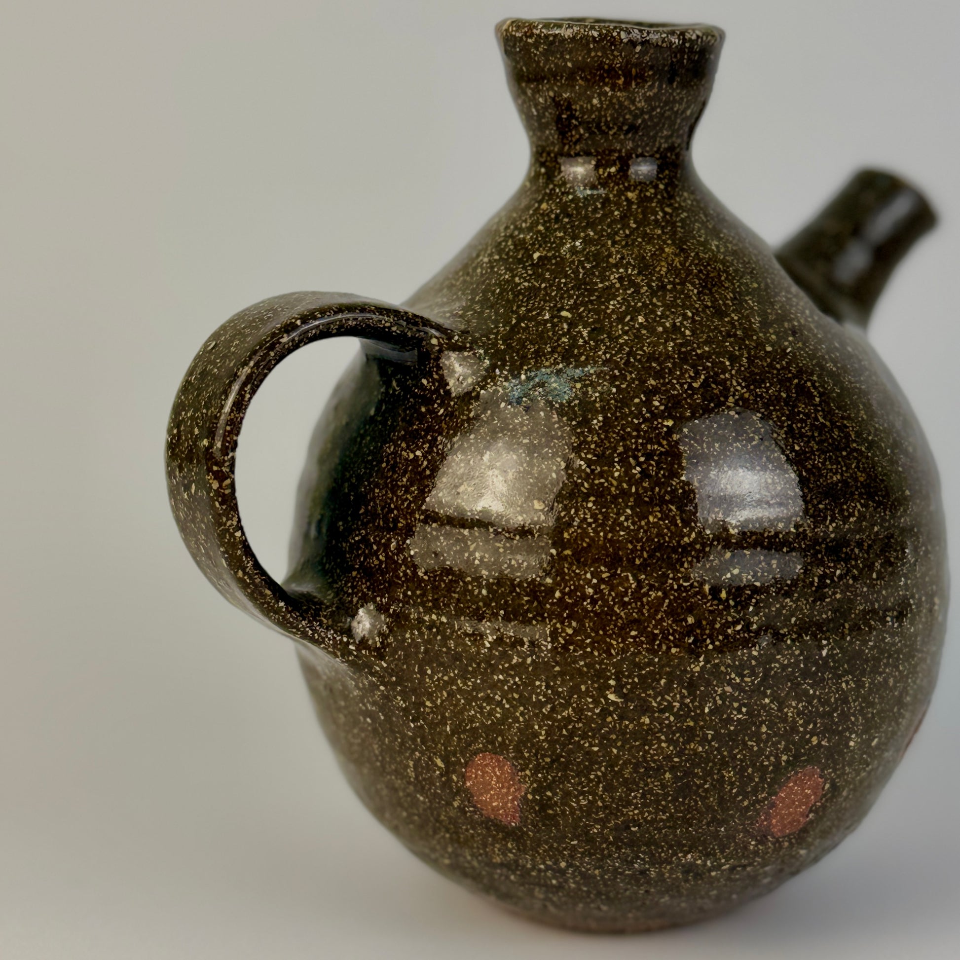 Brown speckled ceramic jug on a plain background