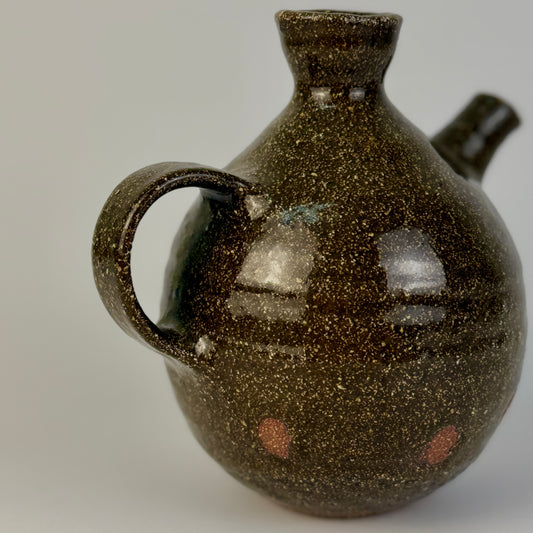 Brown speckled ceramic jug on a plain background