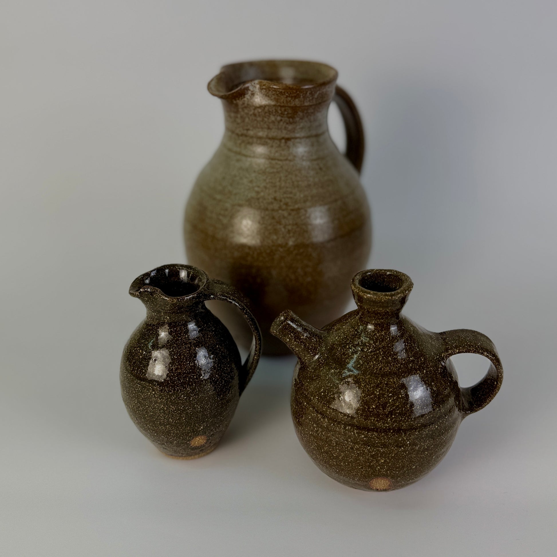 Three brown ceramic jars on a gray background