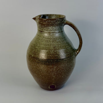 Brown ceramic pitcher on a gray background