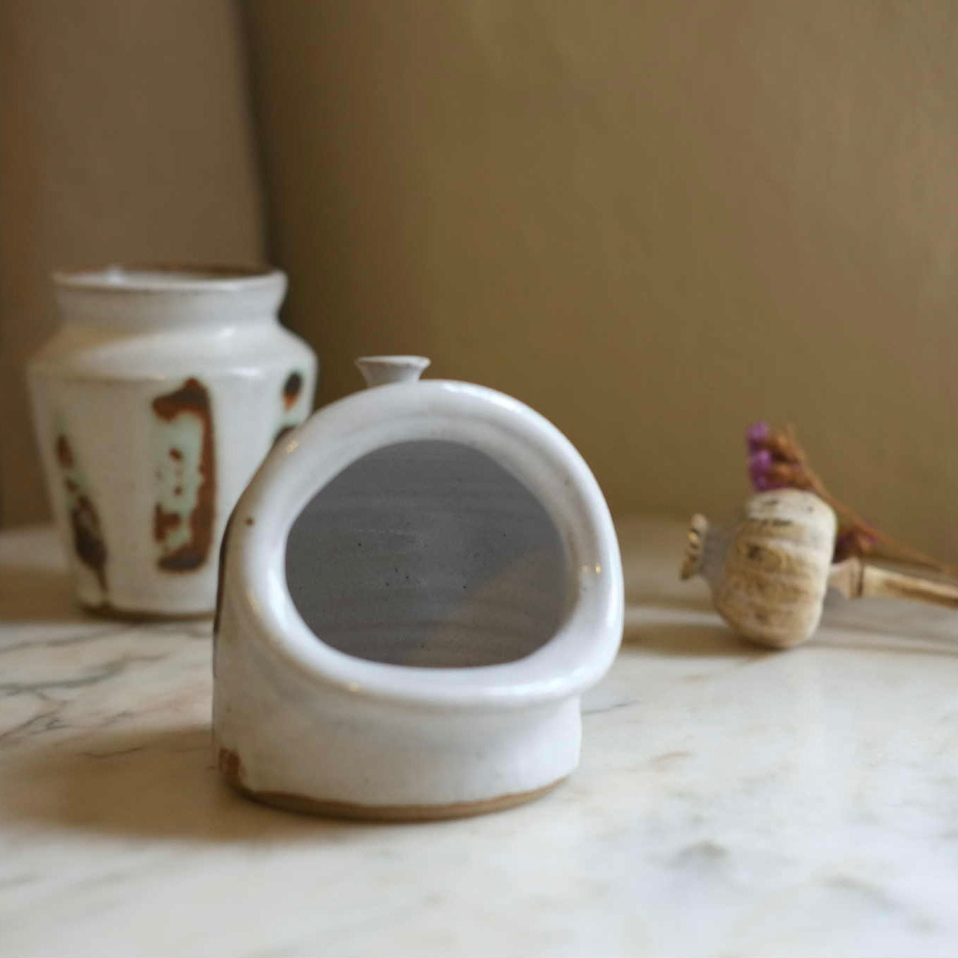 Ceramic saltpig and other studio pottery on a marble surface with a neutral background