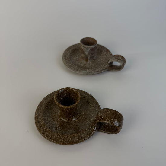 Two brown ceramic candle holders on a white background
