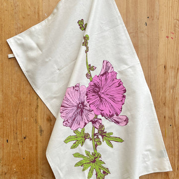 White towel with pink floral design on a wooden surface