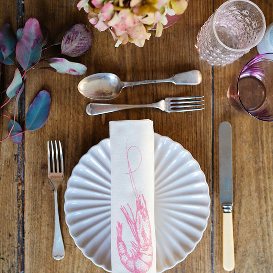 a set table featuring a rolled up napkin with prawn illustration