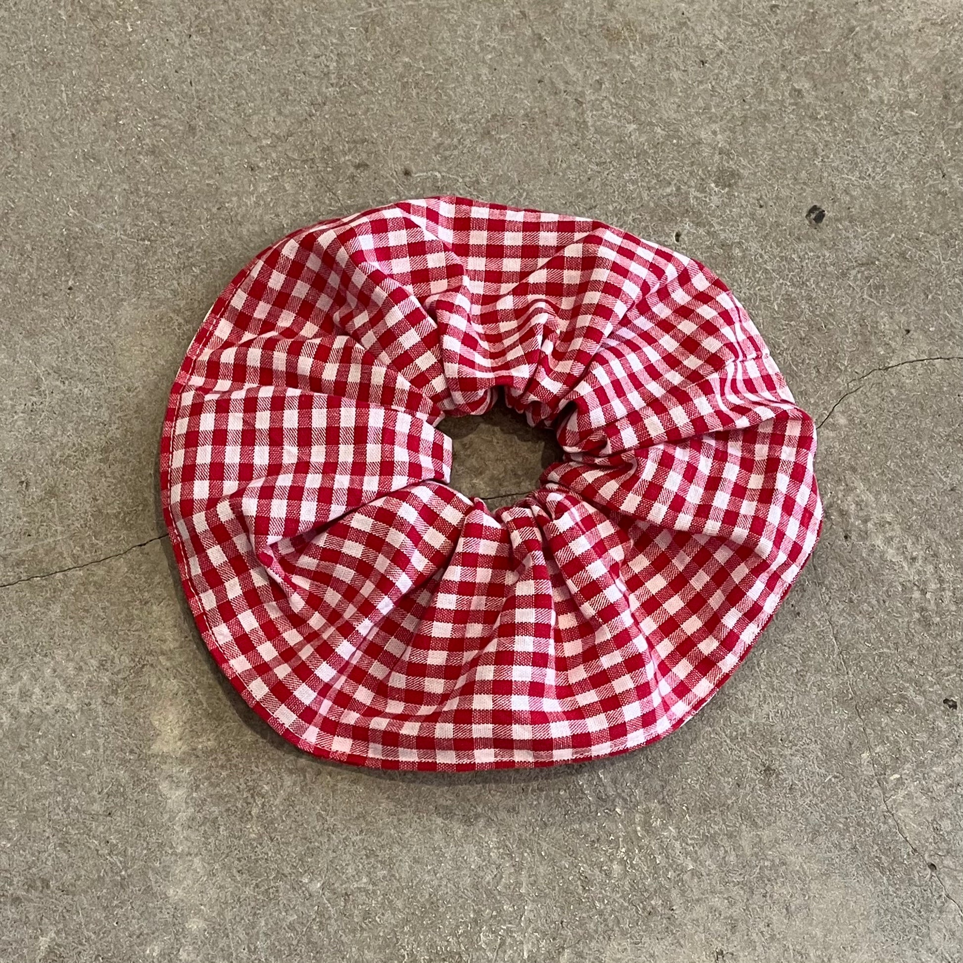 Red and white checkered scrunchie on a gray concrete surface
