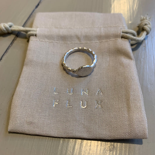 A silver ring on a fabric pouch