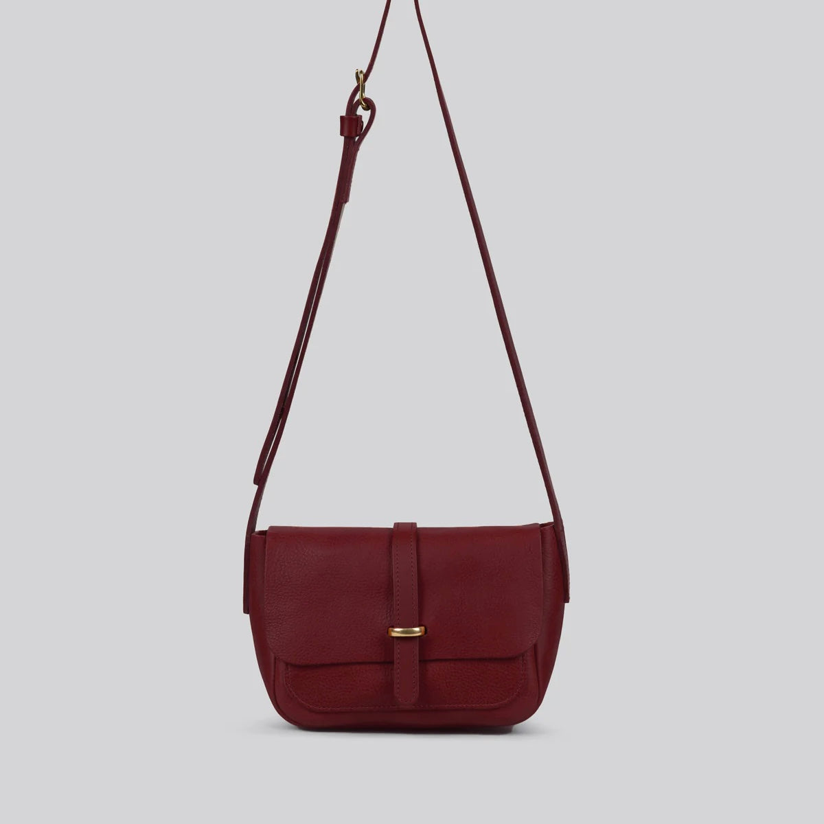 Maroon Red shoulder bag with a strap and brass details on a light gray background