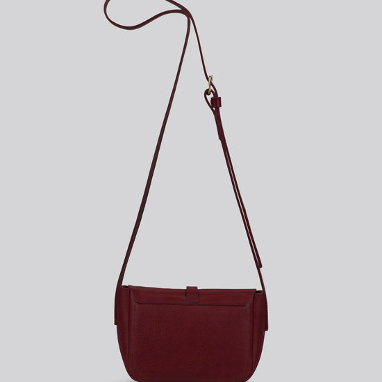 Maroon artisan leather shoulder bag with a strap on a light gray background