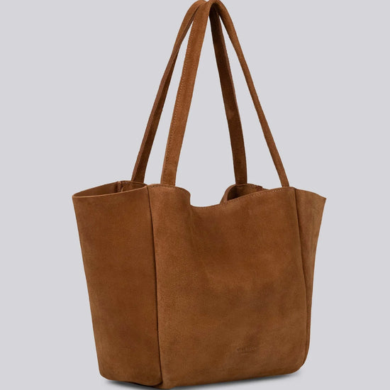 Brown suede luxury tote bag with long handles on a light gray background