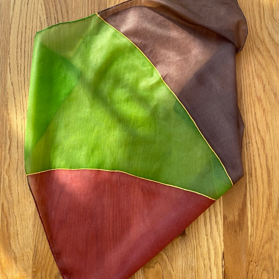 Color-blocked fabric sample with green, brown, and red on a wooden surface