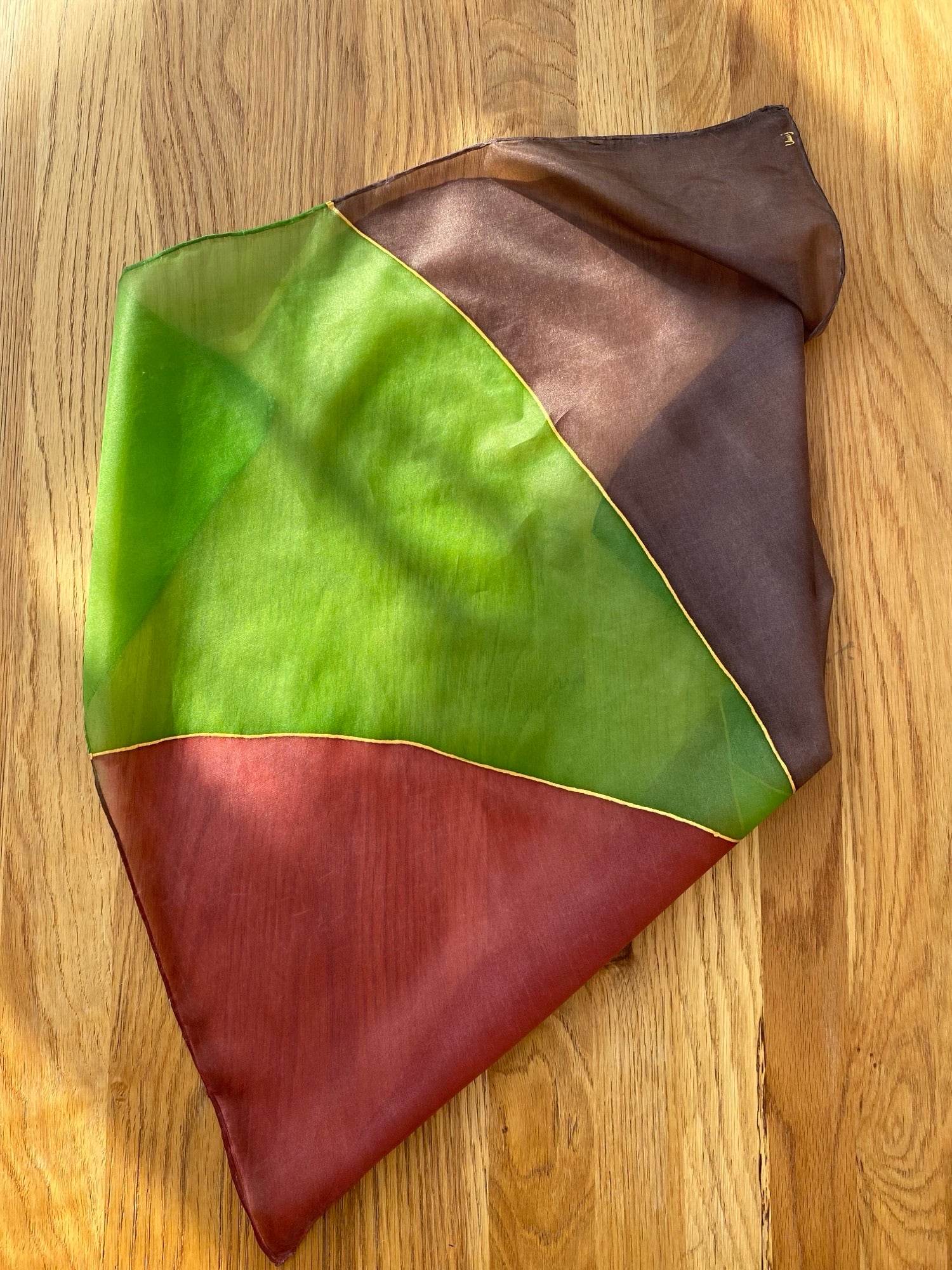 Color-blocked fabric sample with green, brown, and red on a wooden surface