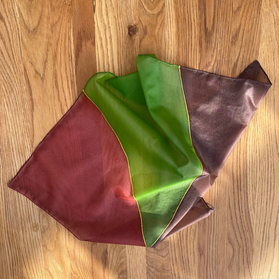 Folded fabric with red, green, and brown colors on a wooden surface