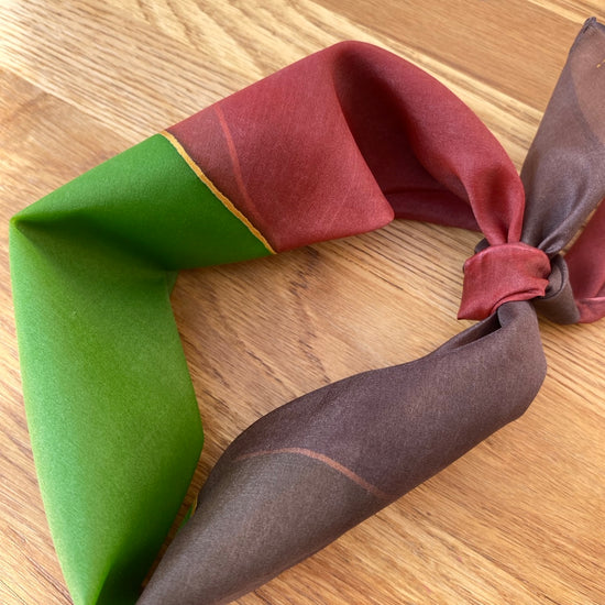 Folded fabric with red, brown, and green colors on a wooden surface