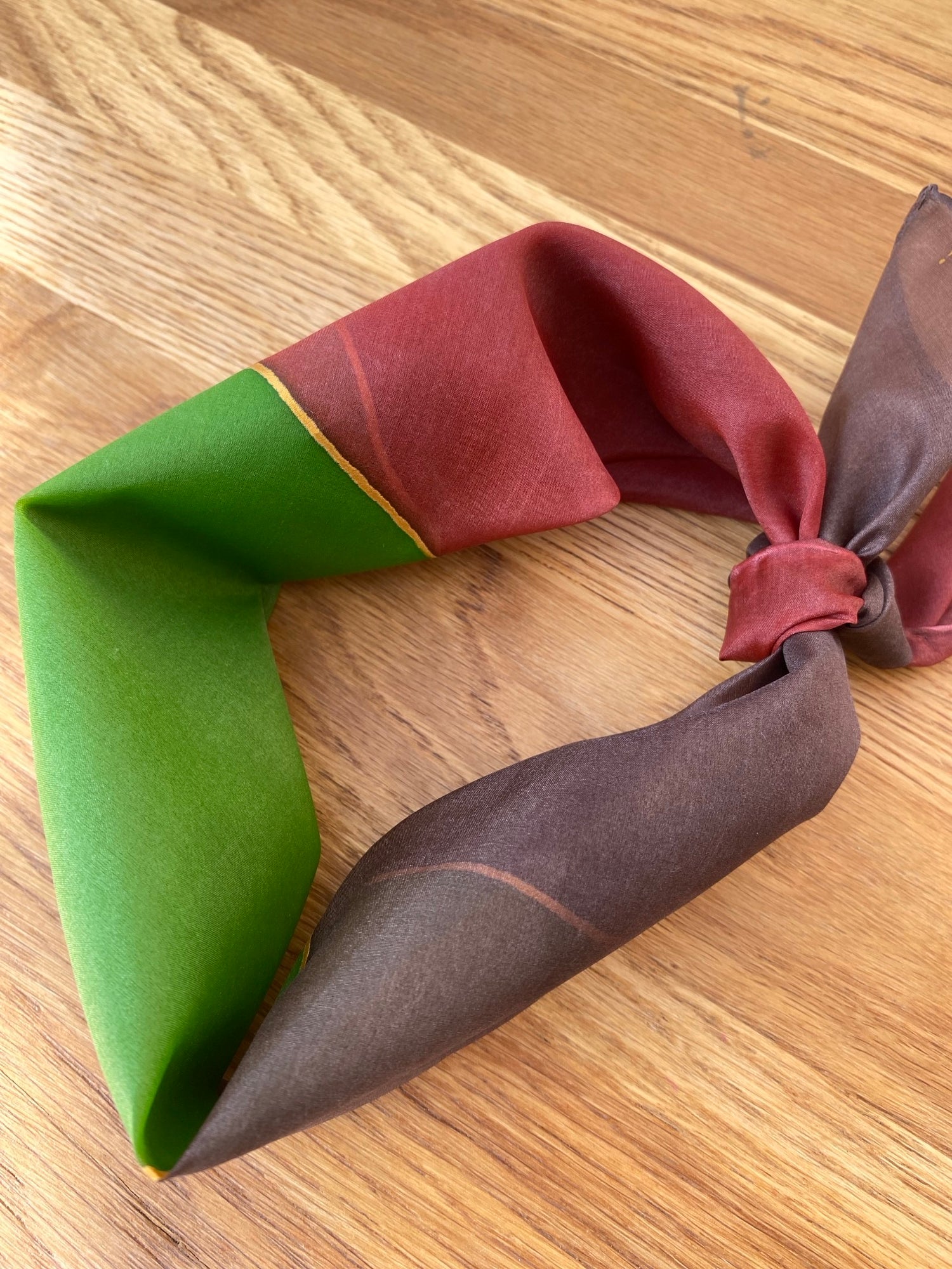Folded fabric with red, brown, and green colors on a wooden surface