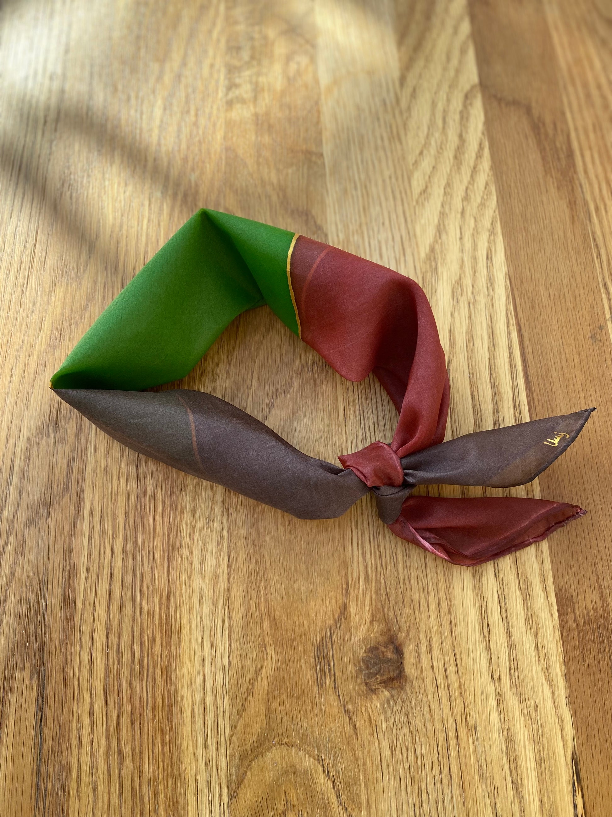 Three-colored  silk neck scarf on a wooden surface