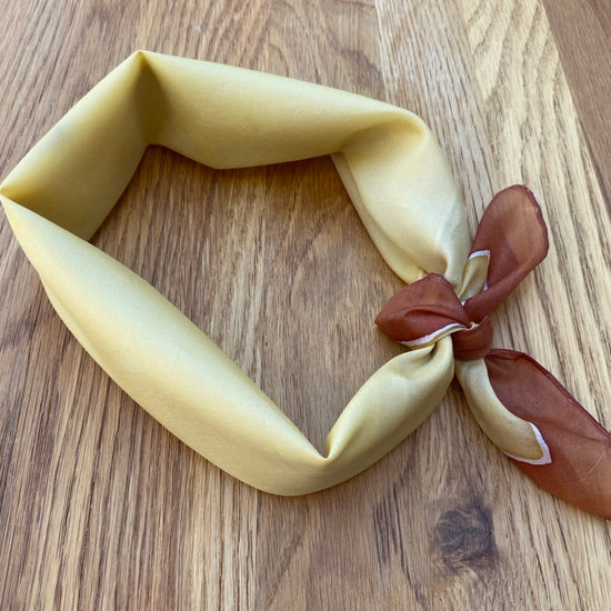 Neatly tied beige and brown scarf on a wooden surface