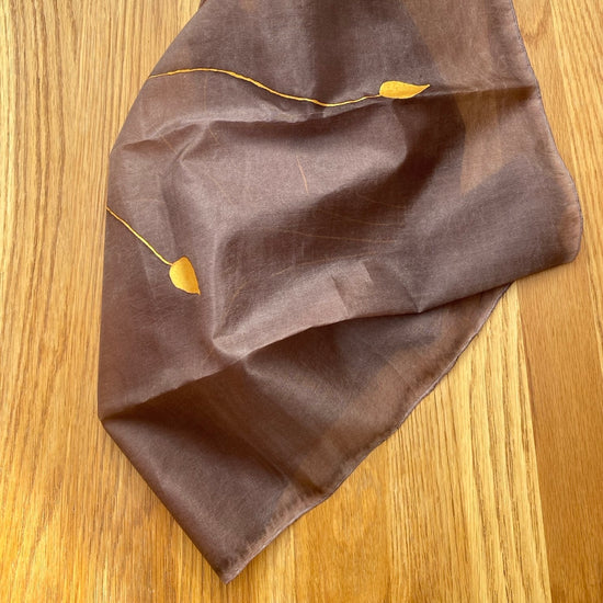 Brown fabric with gold leaf patterns on a wooden surface