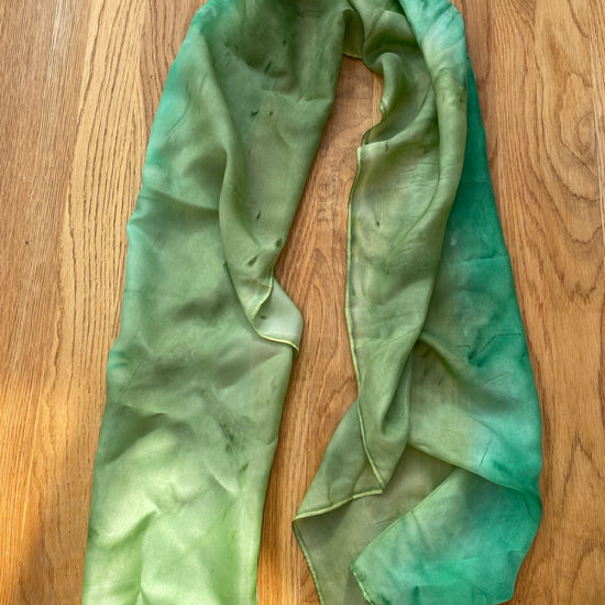 Long green silk scarf on wooden background
