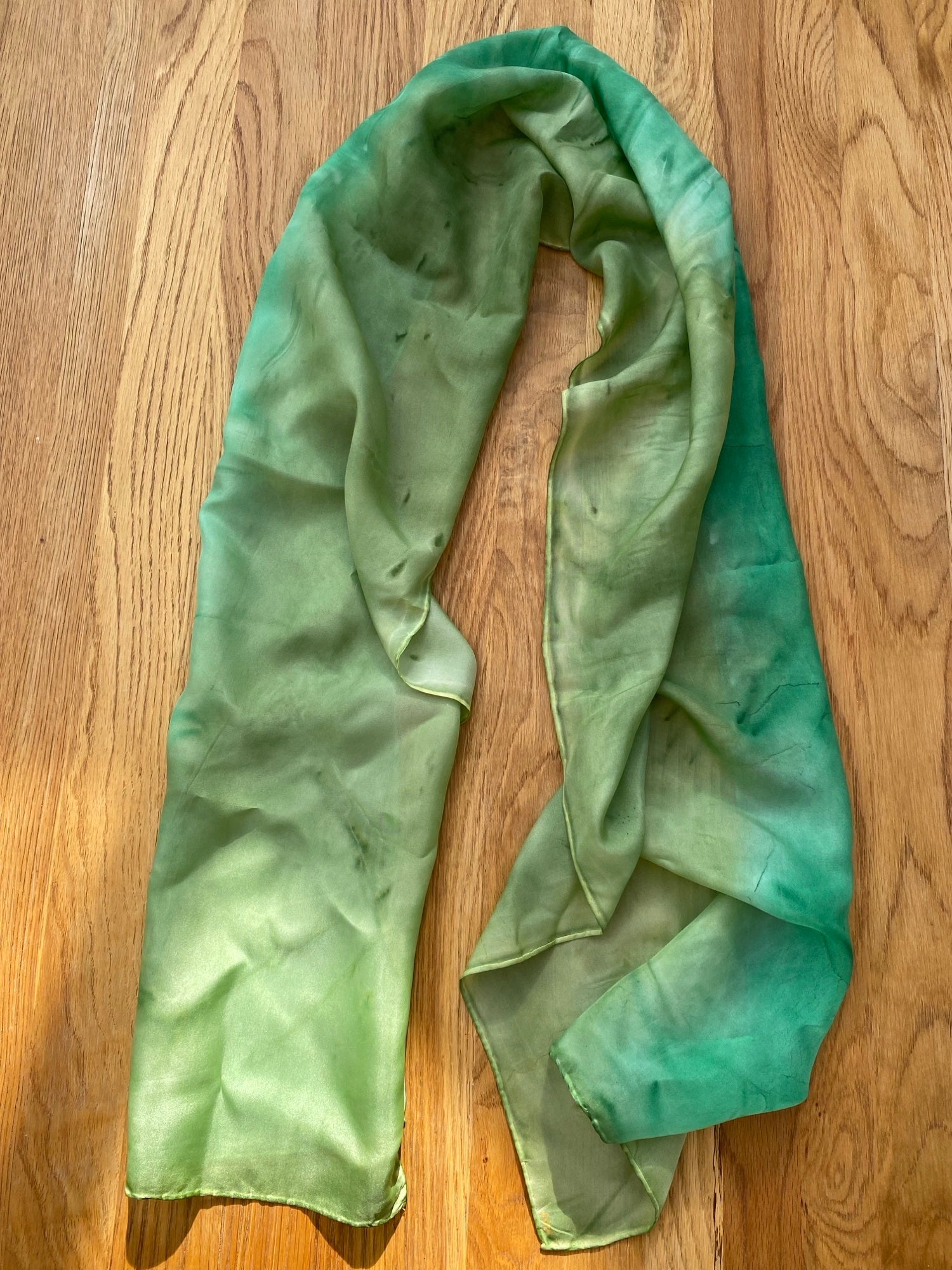 Long green silk scarf on wooden background