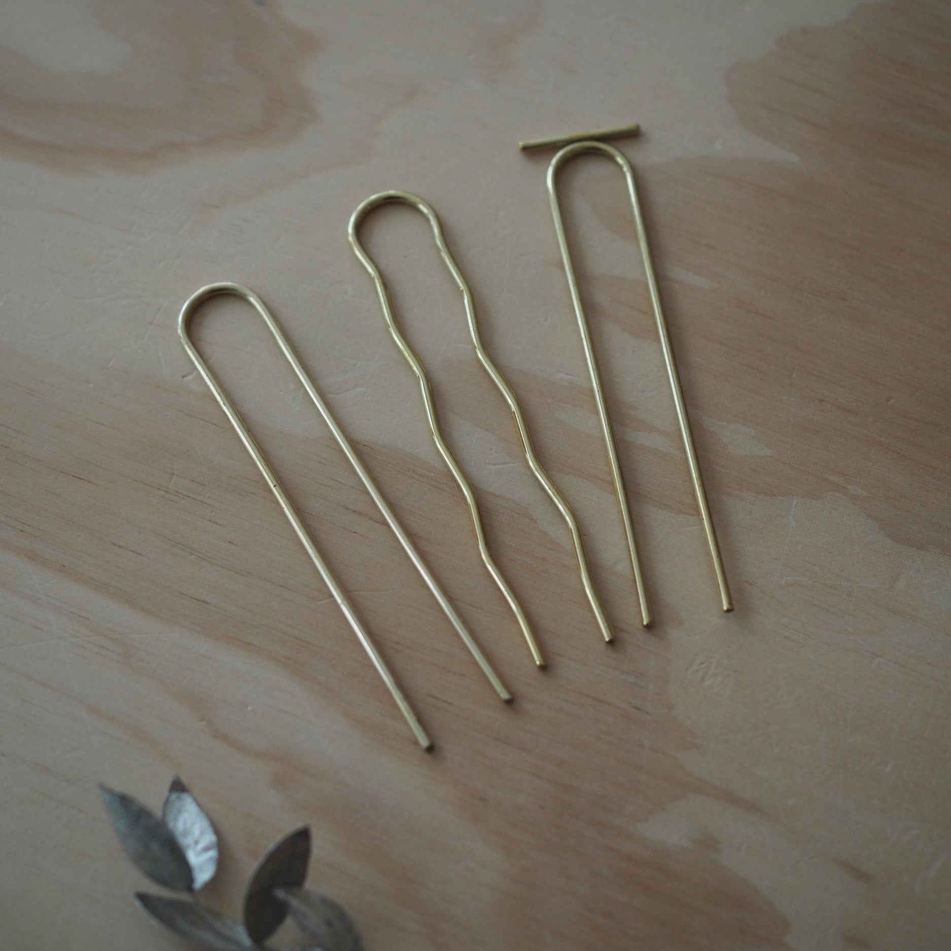 Three gold tent stakes on a wooden surface
