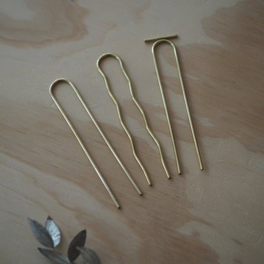 Three gold tent stakes on a wooden surface