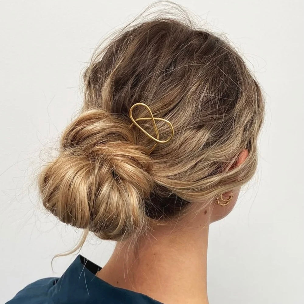 Person with styled hair featuring a gold hair pin on a plain background