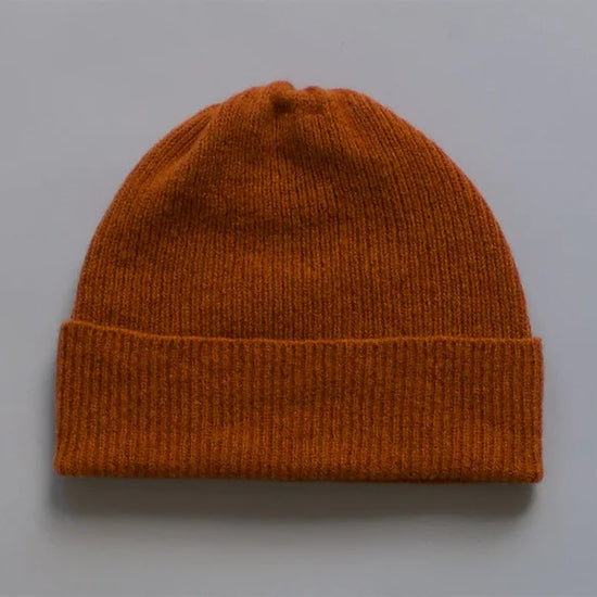 Orange knit beanie on a grey background