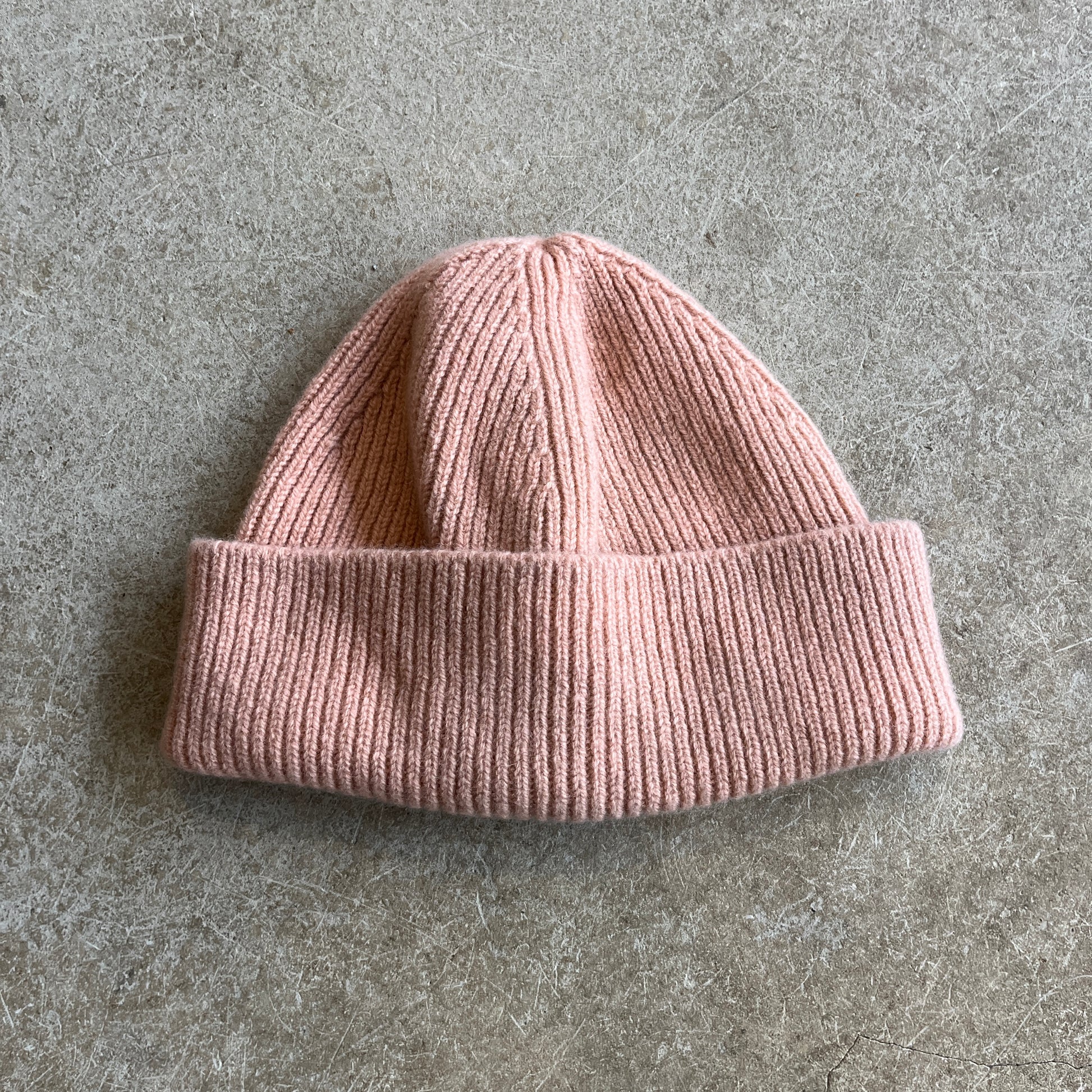Pink knit beanie on a grey surface