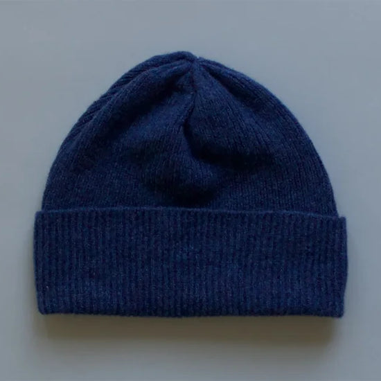 Blue knit beanie on a light grey background