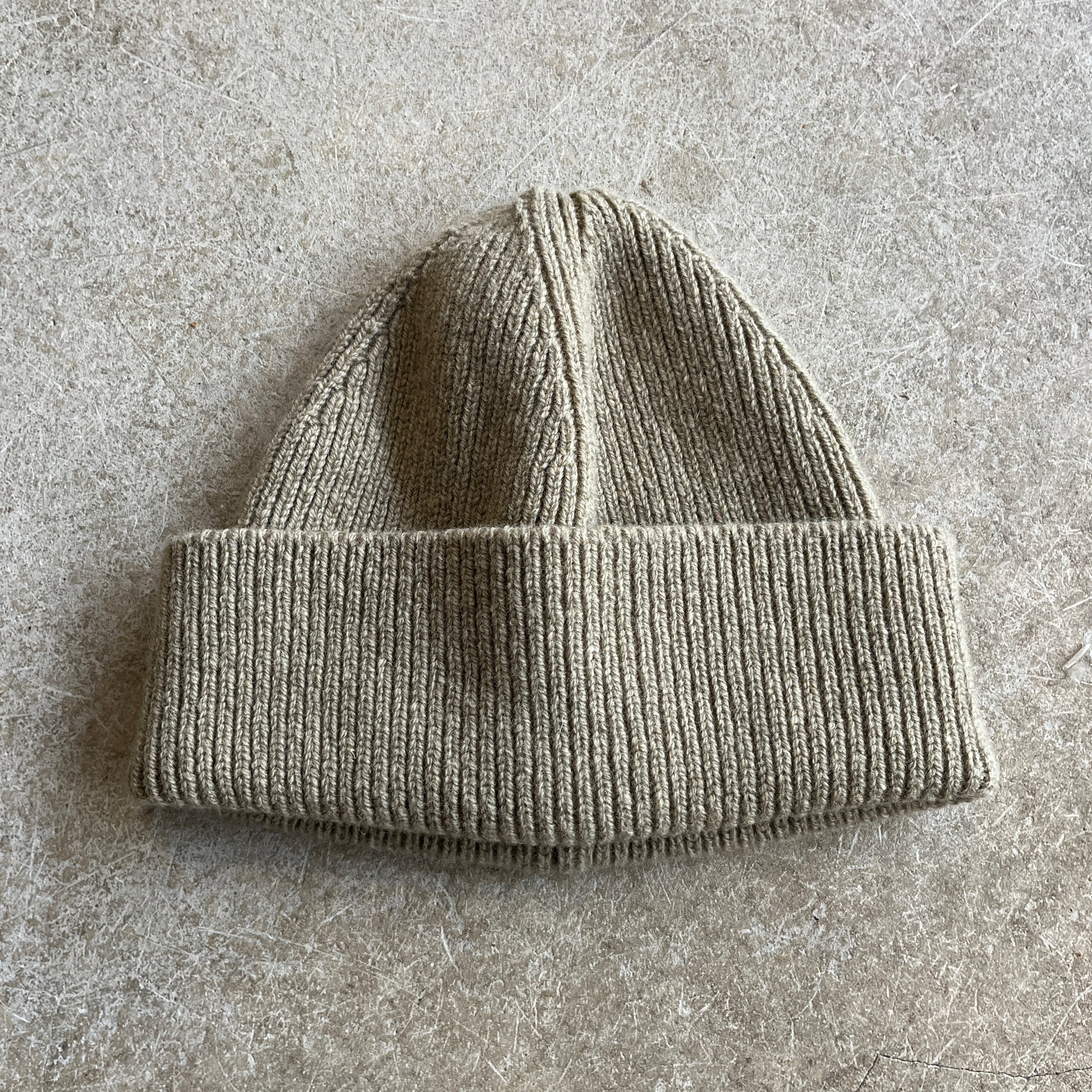 Gray knit beanie on a textured grey surface