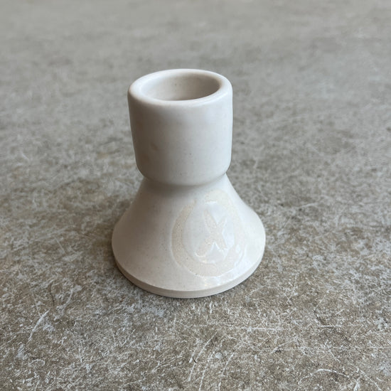 White ceramic candle holder on a gray surface