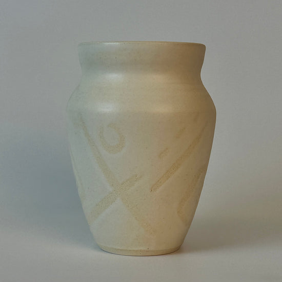 Beige ceramic vase with subtle patterns on a plain background