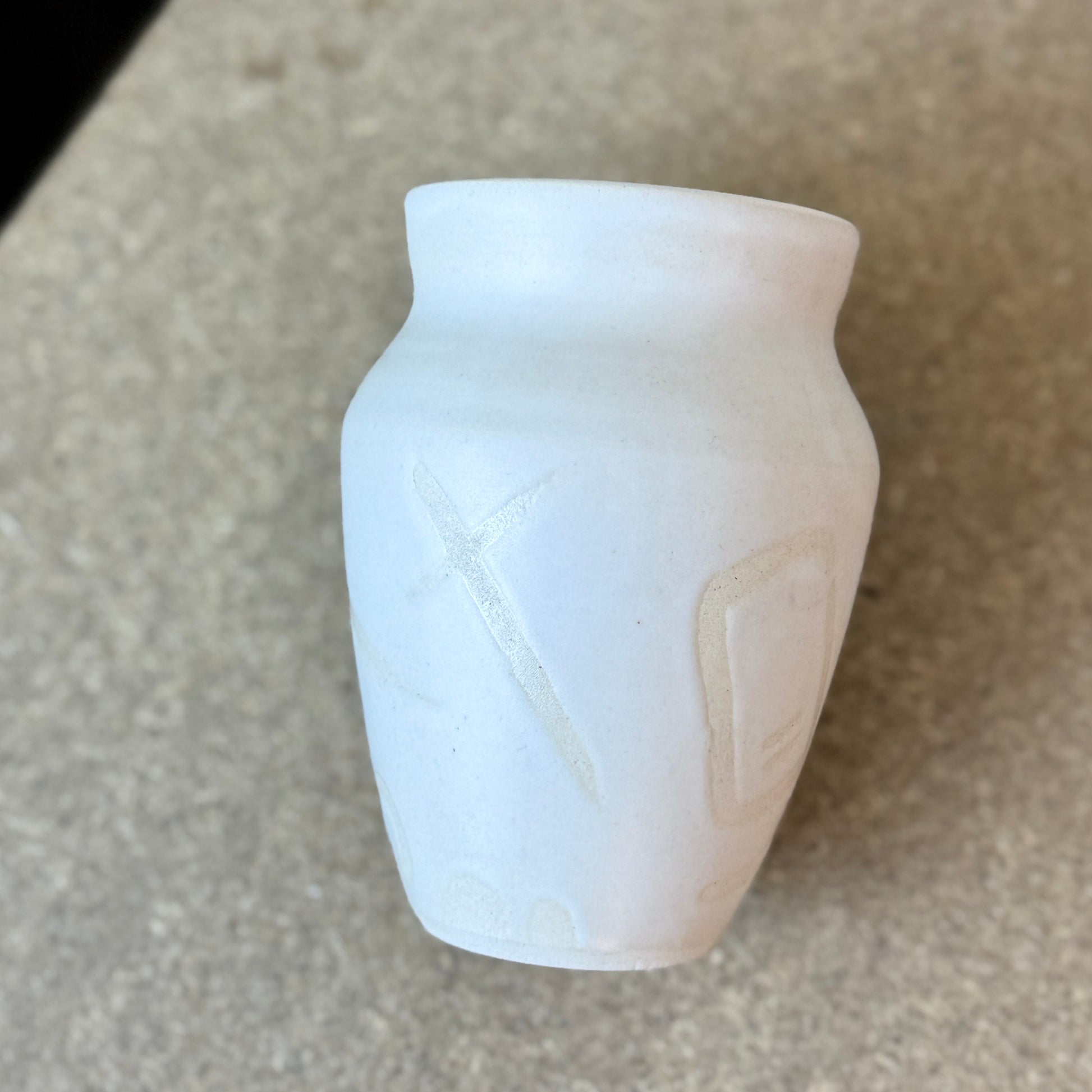 Small white vase with a textured surface on a beige background