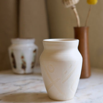 White ceramic vase on a marble surface with blurred background