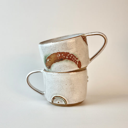 Two ceramic mugs stacked on a light background
