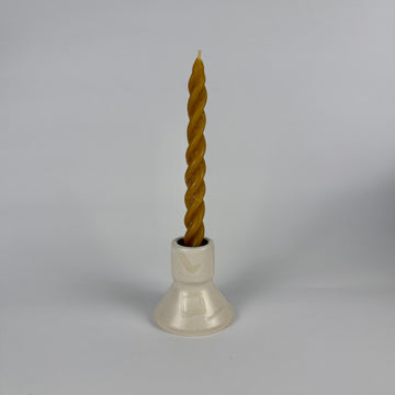 Twisted candle in a white holder on a gray background