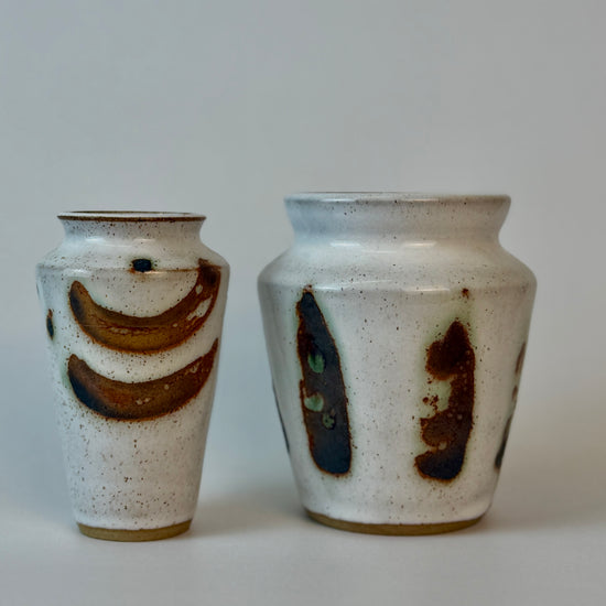 Two ceramic vases with brown and black abstract designs on a plain background