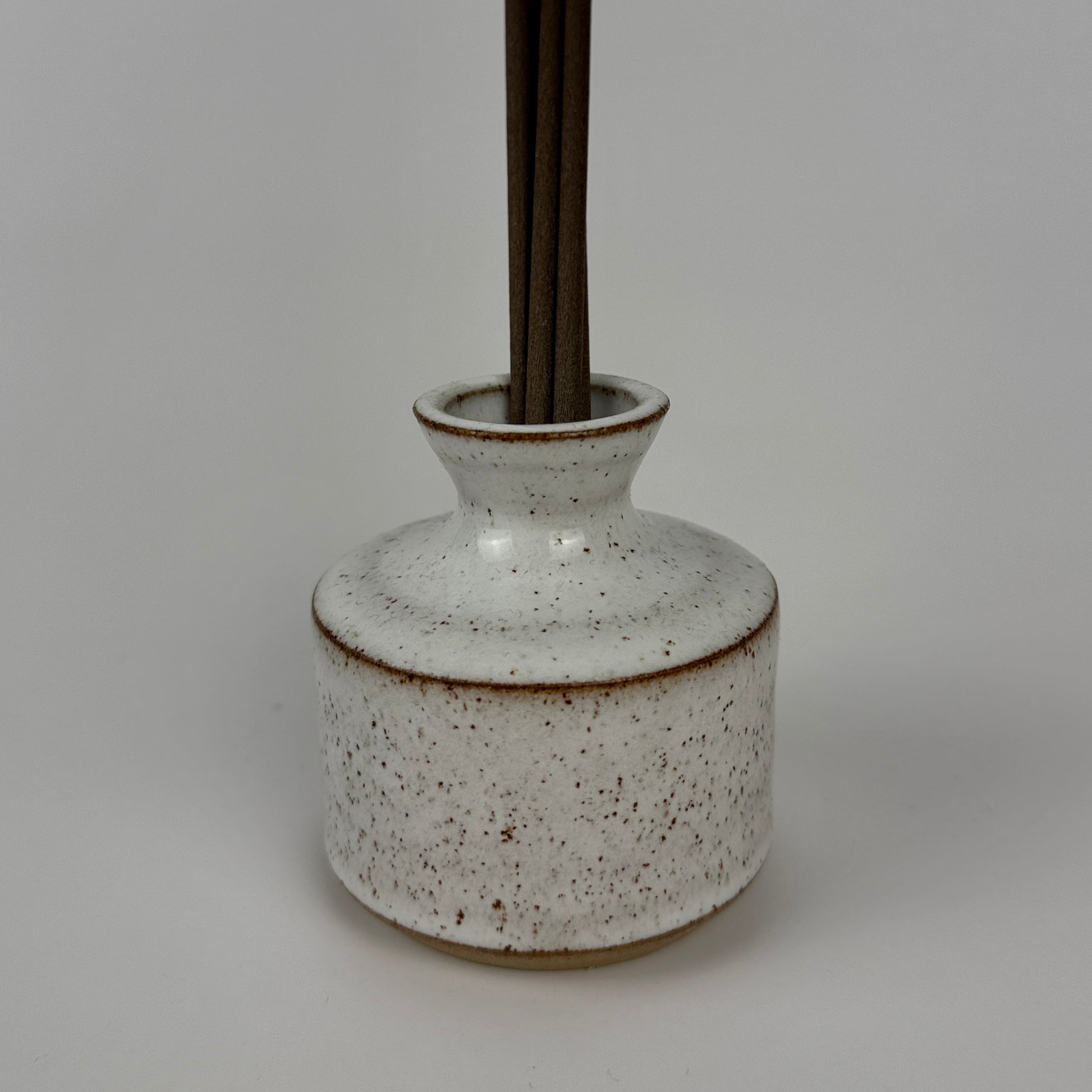 Speckled ceramic bottle with a dark brown base on a gray background