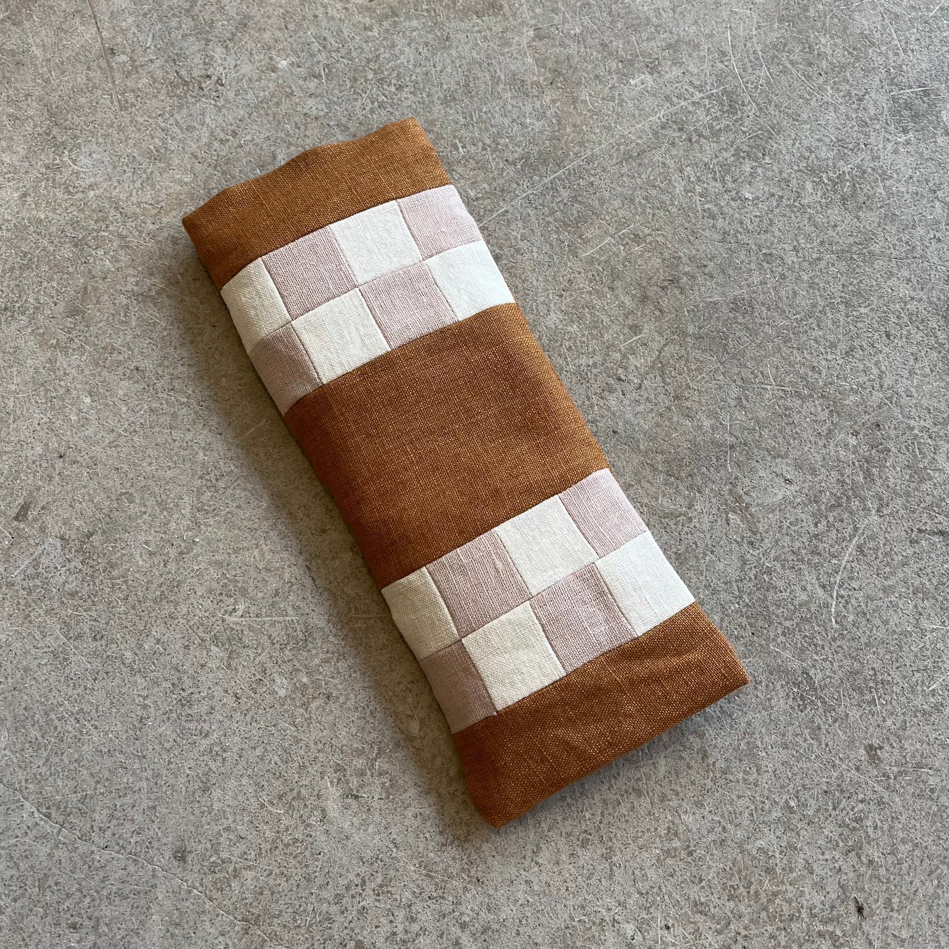 Folded brown fabric with a checkered pattern on a gray surface