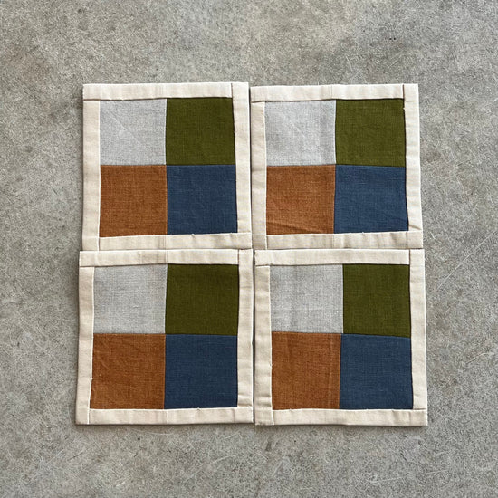Four square coasters with a geometric pattern on a gray surface