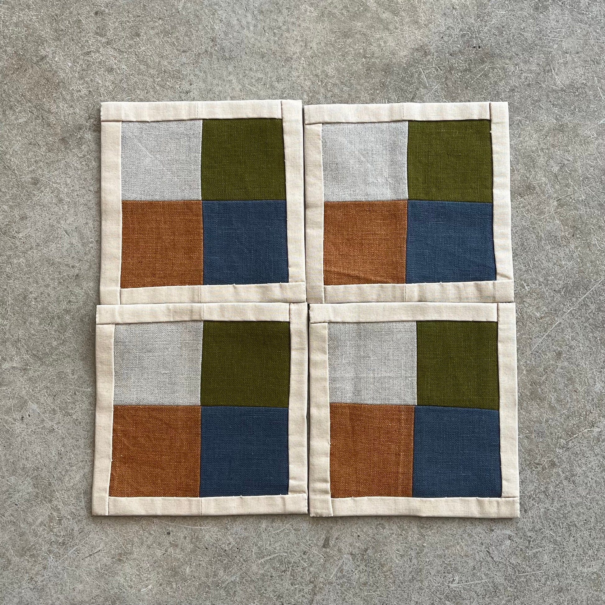 Four square coasters with a geometric pattern on a gray surface