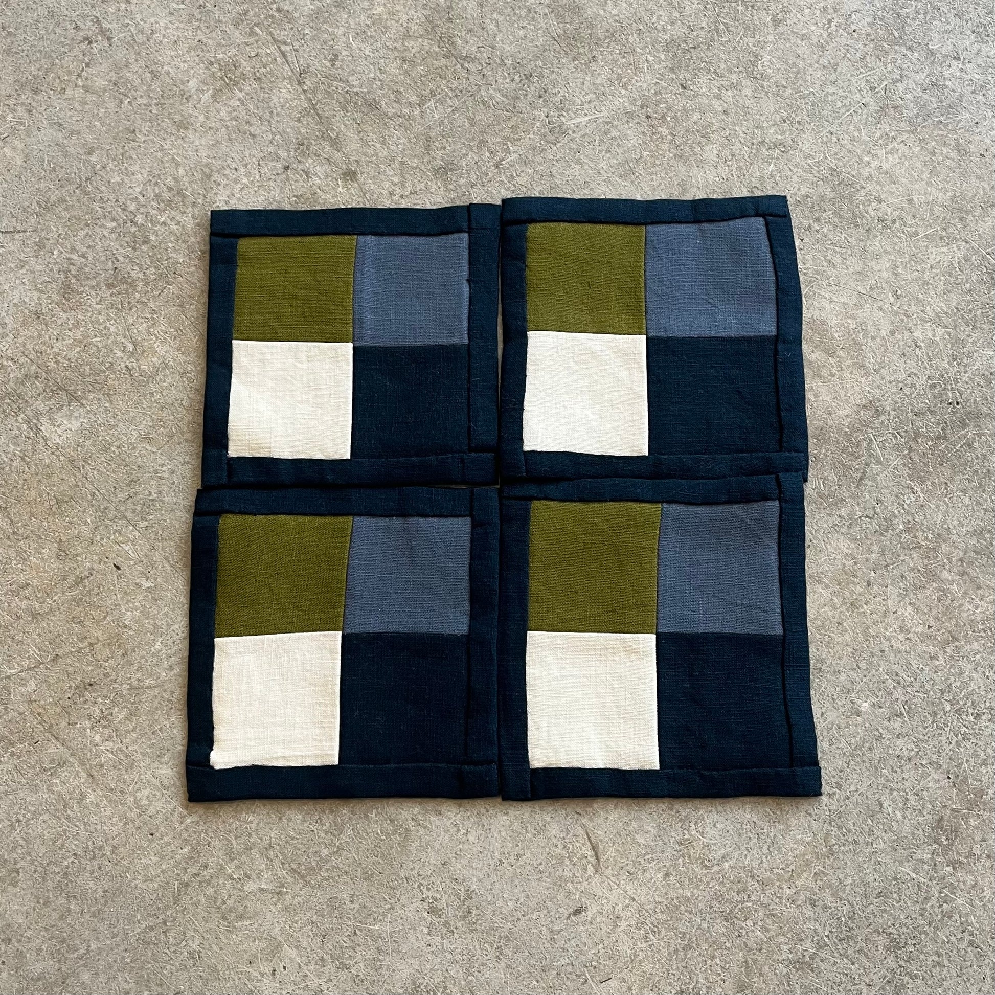 Checkered fabric square with green, blue, and white squares on a gray surface