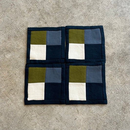 Checkered fabric square with green, blue, and white squares on a gray surface