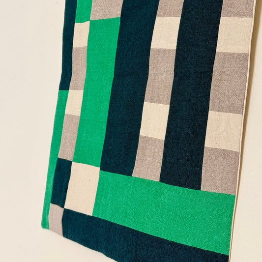 Fabric with green, navy, and beige checkered pattern on a neutral background