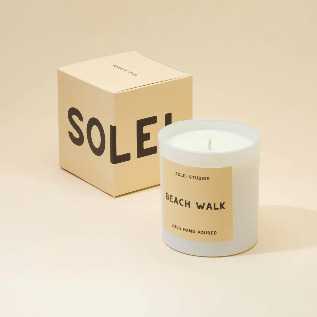 Candle labeled 'Beach Walk' by SOLEI STUDIOS with packaging on a beige background